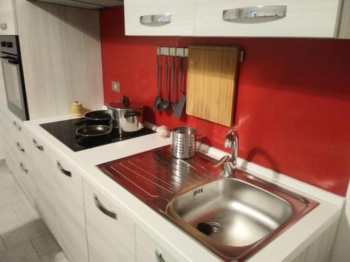 uma cozinha com um lavatório e uma parede vermelha em La casina di Laura em Maglie
