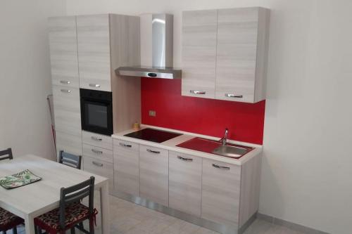 uma cozinha com armários brancos e uma parede vermelha em La casina di Laura em Maglie