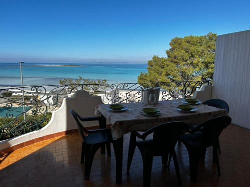 a table on a balcony with a view of the ocean at Villa GAUDÌ in Sant'Isidoro