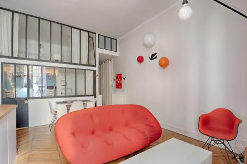 un salon avec une chaise rouge et une table dans l'établissement Studio Loft des Combes - Welkeys, à Paris