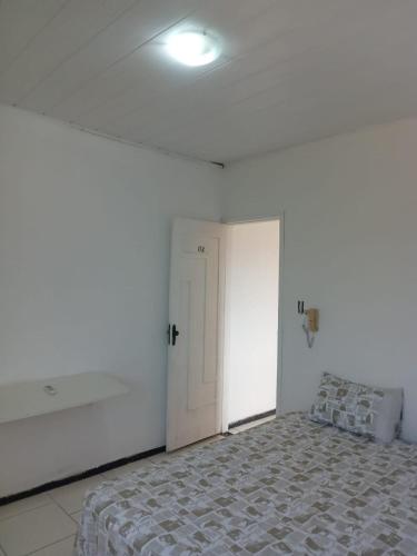 ein weißes Zimmer mit einem Bett und einer weißen Tür in der Unterkunft Pousada Bahamas in Neópolis