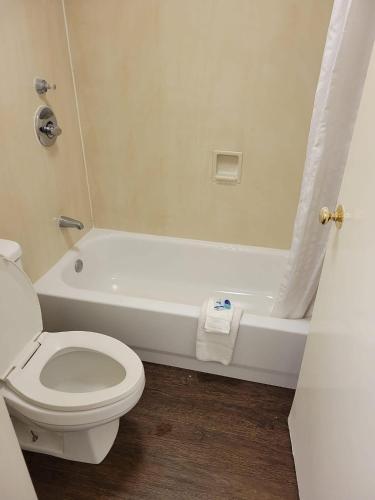 a bathroom with a toilet and a bath tub with at Rodeway Inn Huntsville West in Huntsville