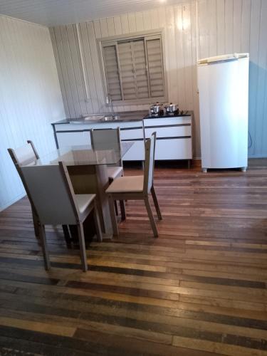 eine Küche mit einem Tisch und Stühlen sowie einem Kühlschrank in der Unterkunft Chalé das cataratas 