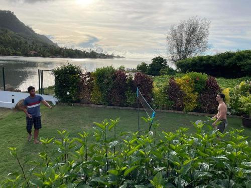 two men playing with a kite in a yard at Villa Ho'a - bord de mer avec piscine in Papetoai
