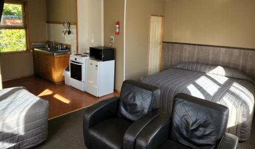 1 dormitorio con cama, silla y lavamanos en Smylies Accommodation, en Springfield