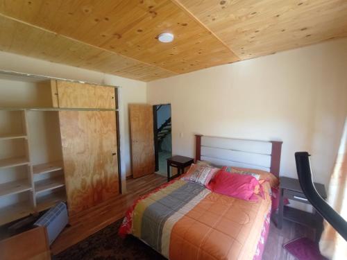 a bedroom with a bed and a wooden ceiling at Complejo La Soplada Hostel&Cabañas in Aluminé