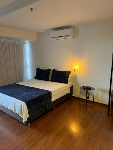 a bedroom with a large bed and a table at Flat Saint Paul Retro in Brasilia