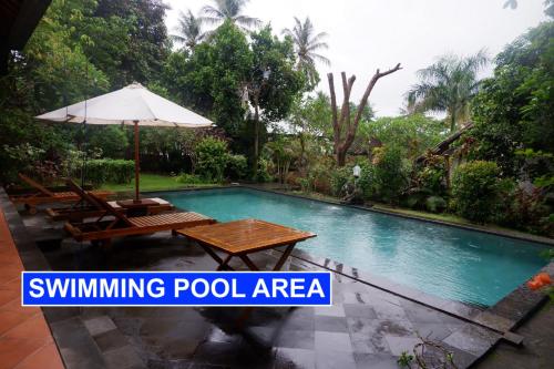uma área de piscina com uma mesa e um guarda-sol em Villa Lombok Senggigi Kamila Forest By Villaloka em Mangsit
