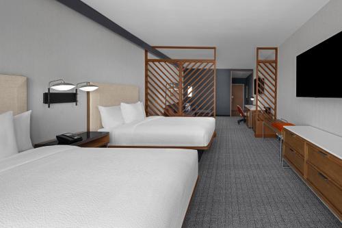 a hotel room with two beds and a flat screen tv at Courtyard by Marriott Orem University Place in Orem