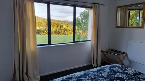 a bedroom with a bed and a large window at Okura River Estate Getaway in Auckland