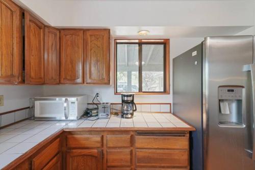 a kitchen with wooden cabinets and a stainless steel refrigerator at Mountain Home w/ a River in Back - Close to Skiing in Beaver