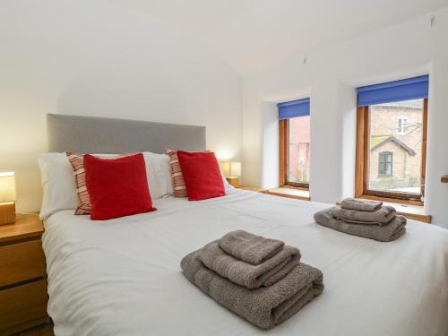 a bedroom with a large white bed with towels on it at Bluebell Cottage in Leominster