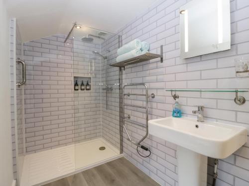 a white bathroom with a shower and a sink at Beekeeper's Cottage in Leominster