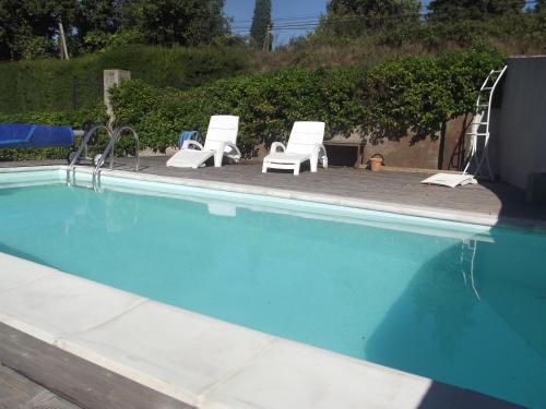 a swimming pool with two lawn chairs and a pair at studio en rez-de-jardin dans la verdure in Aix-en-Provence
