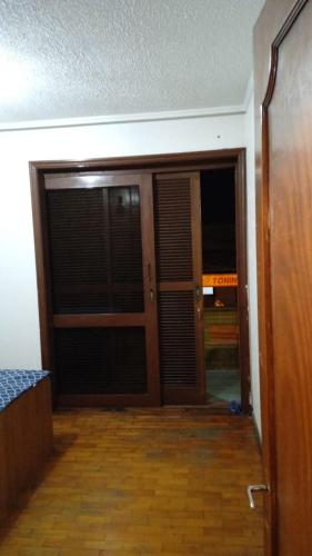 een lege kamer met een deur en een kamer met een houten vloer bij Quarto superior com sacada. in Caxias do Sul