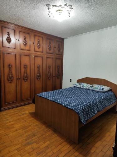 um quarto com uma cama com armários de madeira e um colchão azul em Quarto superior com sacada. em Caxias do Sul