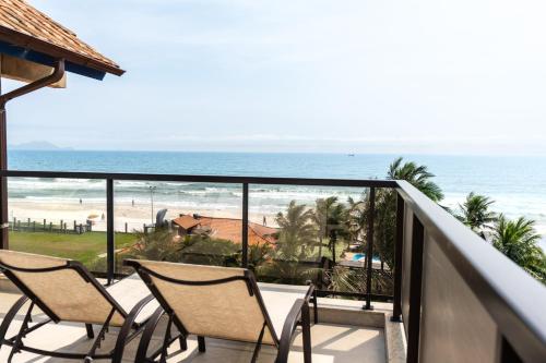 a balcony with two chairs and a view of the beach at Costa Norte Ingleses Hotel in Florianópolis