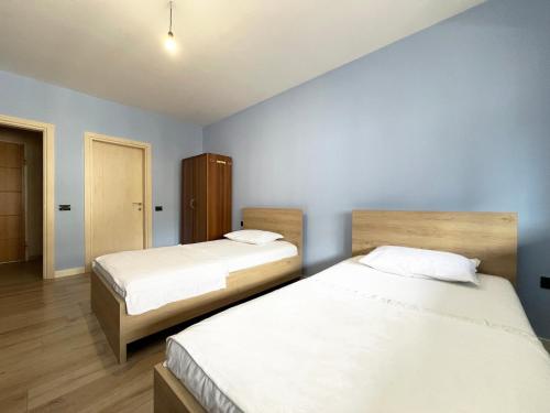 2 Betten in einem Zimmer mit blauen Wänden in der Unterkunft B2 Apartment in Tirana