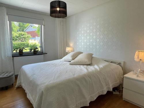 1 dormitorio con cama blanca y ventana en Holiday home MYGGENäS II, en Myggenäs