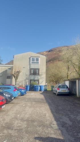 a parking lot with cars parked in front of a building at Budget Rooms in Fort William