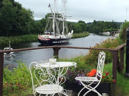 a table and chairs and a boat in a river at Sealladh Sona in Inverness