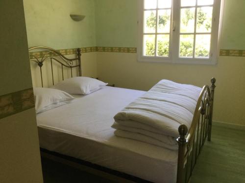 une chambre avec un lit avec des draps blancs et une fenêtre dans l'établissement Gites De La Grasse, à Carcassonne