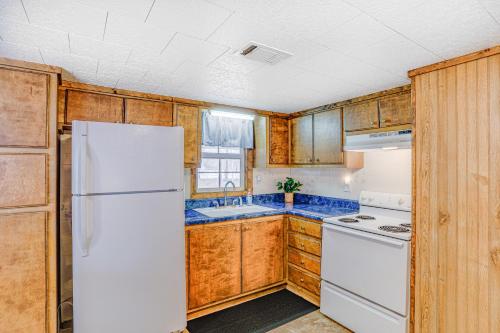 a kitchen with a white refrigerator and wooden cabinets at Heber Springs Cabin with Deck 3 Mi to Sugarloaf Mtn in Heber Springs