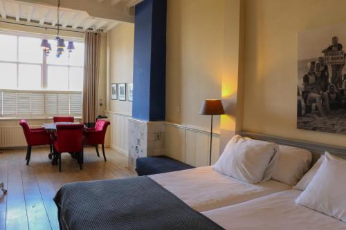 a hotel room with a bed and a dining table at Auberge de Campveerse Toren in Veere