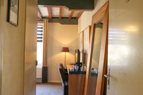 a room with a desk with chairs and a lamp at Auberge de Campveerse Toren in Veere