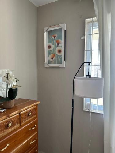 a room with a lamp and a dresser and a window at The Shelton - Sinclair in Montego Bay