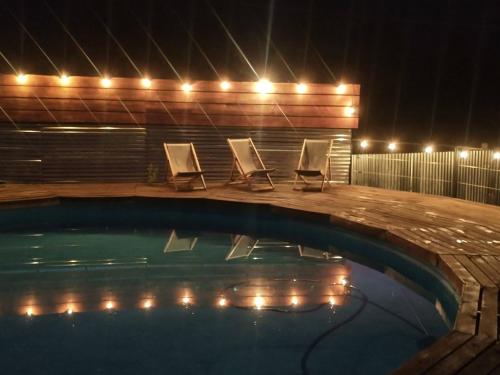 a swimming pool with two lounge chairs and lights at Las Pitras Lodge in Epuyén