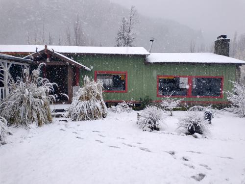 a house covered in snow in front at Las Pitras Lodge in Epuyén