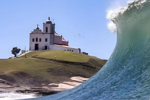 a wave in front of a lighthouse at Cobertura Pôr do Sol Saquarema in Saquarema