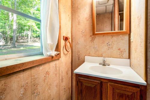 La salle de bains est pourvue d'un lavabo et d'une fenêtre. dans l'établissement Hot Tub, Huge Deck, WiFi, Fire Pit at Chalet Cabin, à Morton Grove