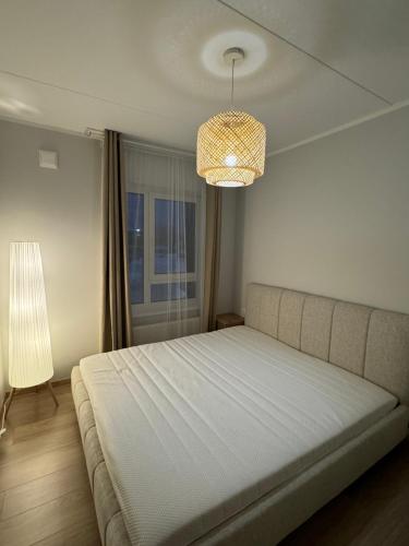 a bedroom with a large bed and a chandelier at Modern 4-Room compact flat with parking in Riga in Dreiliņi