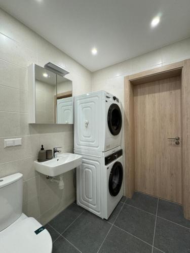 y baño con lavadora y secadora de ropa y lavamanos. en Modern 4-Room compact flat with parking in Riga en Dreiliņi