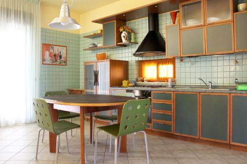 cocina con mesa de madera y sillas verdes en Villa Sam en Comiso