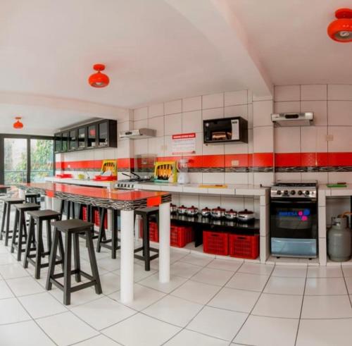 a large kitchen with red and white cabinets and stools at Alpes Huaraz in Huaraz