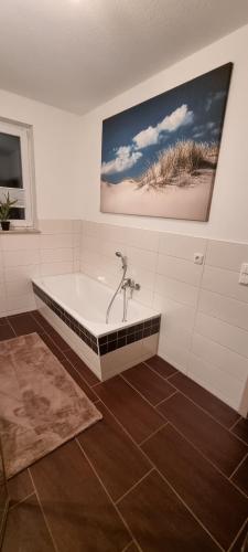 a bathroom with a bath tub with a picture on the wall at Ferienwohnung Maasch in Vierraden