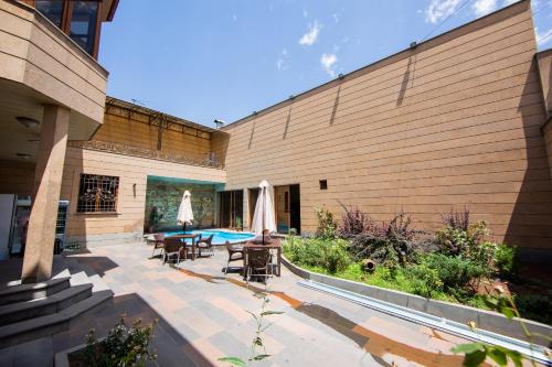 eine Terrasse mit Tischen und Sonnenschirmen neben einem Gebäude in der Unterkunft Villa Hotel in Yerevan