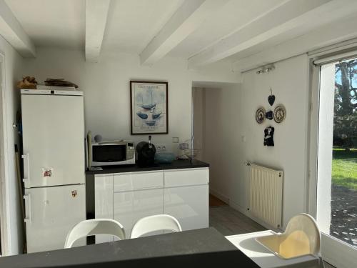 une cuisine avec des armoires blanches et un micro-ondes dans l'établissement Bretzelhouse, à Plouharnel