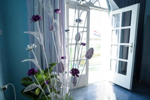 a vase filled with purple and white flowers next to a door at Pension More in Šibenik