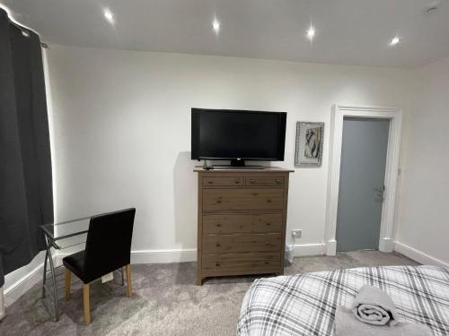 a bedroom with a flat screen tv on a dresser at Rock Lane Rooms in Birkenhead