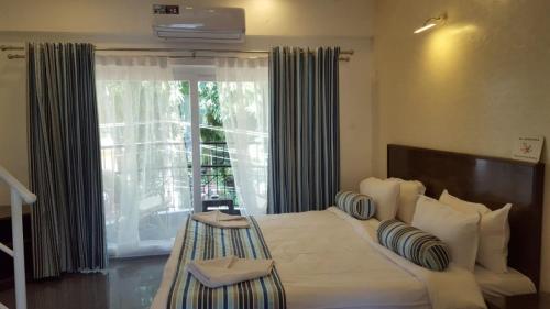 a bedroom with a large bed with a large window at Pool View Studio Apartment in Candolim Beach Resort in Baga
