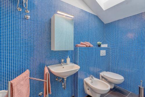 a blue tiled bathroom with a sink and a toilet at Diamond Seaview Penthouse in Peroj