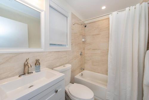 a bathroom with a toilet and a sink and a tub at Modern Condo-NYC@Fingertips in North Bergen