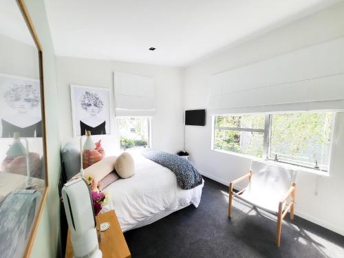 オークランドにあるInner City Sunny Bedroomのベッドと椅子のある白い寝室
