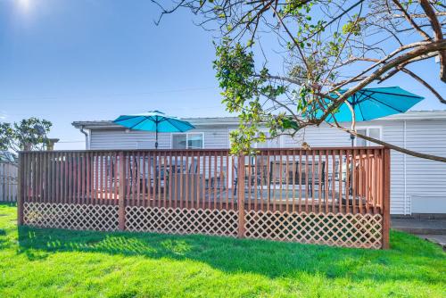 a fence with two blue umbrellas in a yard at Cozy PNW Getaway with Fire Pit Walk to Beach! in Moclips