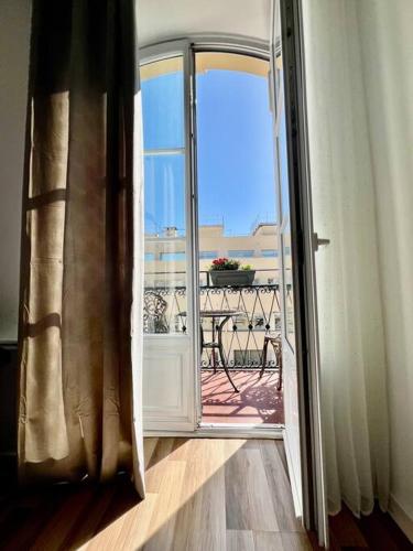 une porte ouverte sur un balcon avec une table dans l'établissement Dezy’s House, à Nice