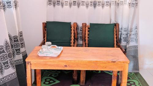 un tavolo in legno con 2 sedie verdi e un tavolo con di Zanz bed and breakfast a Nungwi